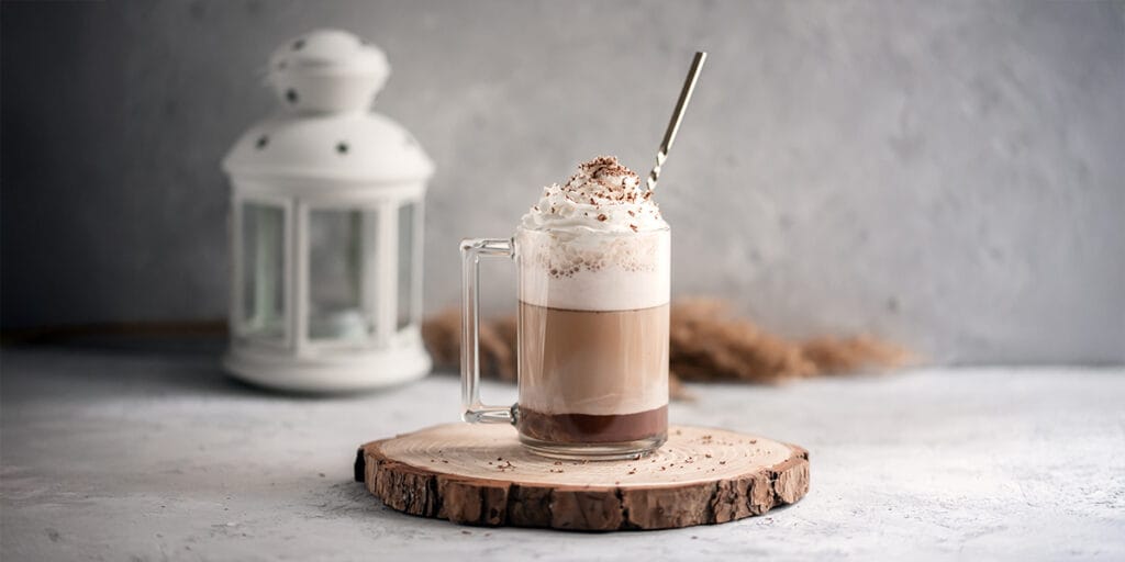 Taş grisi bir arka plan üzerinde ahşap bir tepsi üzerinde çırpılmış krema ile mocha.