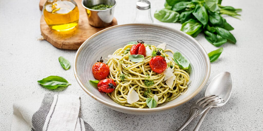 Gri kasede pesto soslu spagetti ve taze fesleğen yaprakları.